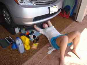 Photo of teen driver changing oil on car.