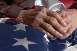 Image of old woman's hands holding an American flag as a metaphor for separating from military service| The-Military-Guide.com