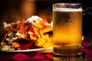 A closeup image of spicy nachos with a cold, frosty mug of beer to show how advertising triggers the urge to drink alcohol. | The-Military-Guide.com