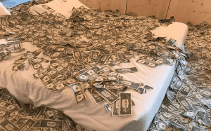 This is an actual image of a room at a hotel lobby in Porto, Portugal-- partly because the hotel had been converted from an old bank building. It was a great way to start a FI Chautauqua week. Image of king-size mattress with dollar bills scattered on top and around the room representing Roth IRA conversions in a high income-tax bracket | MilitaryFinancialIndependence.com