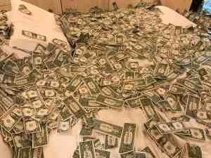 This is a photo of fake money scattered around a display room in the lobby of the Zero Box Lodge in Porto, Portugal, which is built in what used to be a bank building. Image of bed covered in fake dollar bills from display room at Zero Box Lodge in Porto, Portugal | The-Military-Guide.com