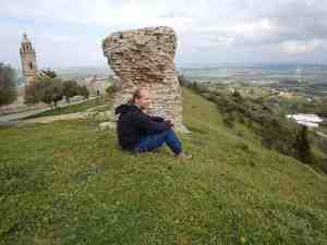 Atop Medina Sidonia next to Roman ruins. Note the cathedral (built on ruins of a mosque) and the power-generation windmills. An image of author Doug Nordman at top of Medina Sidonia Andalucia Spain. | The-Military-Guide.com