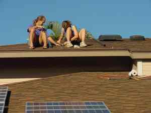 Two people on the roof of a house installing a solar water heating panel