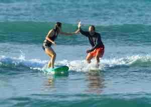 Photo of parent and daughter surfing together.