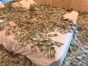 Image of a bed covered with dollar bills. | The-Military-Guide.com