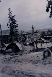 Image of the Philippine town of Olongapo after the eruption of Mount Pinatubo, with the streets covered in ash and people walking alongside to check for survivors and damage. These buildings collapsed under the weight of the ash and the force of the winds. | MilitaryFinancialIndependence.com