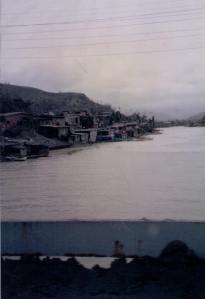 Image of the Philippine town of Olongapo after the eruption of Mount Pinatubo, with the streets covered in ash and people walking alongside to check for survivors and damage. The typhoon's storm surge also flooded out these homes along the river. | MilitaryFinancialIndependence.com