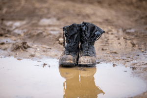 U.S. military black boots by mud puddle symbolizing the 1990s drawdown after the Cold War. Photo digital rights bought from MilstockTribe. | MilitaryFinancialIndependence.com