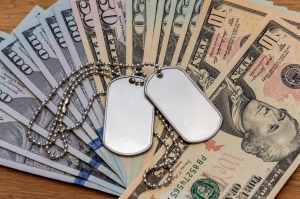 Image of military ID dogtags on top of a pile of U.S. currency as an example of a military payday loan. | MilitaryFinancialIndependence.com