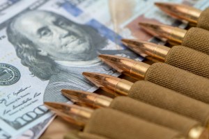 I tried to find a silver bullet to represent making Roth IRA contributions now instead of Roth IRA conversions later... Image of cartridges in a bandolier on top of a hundred-dollar bill representing the concept of military families making Roth IRA contributions now instead of doing Roth IRA conversions later. | MilitaryFinancialIndependence.com